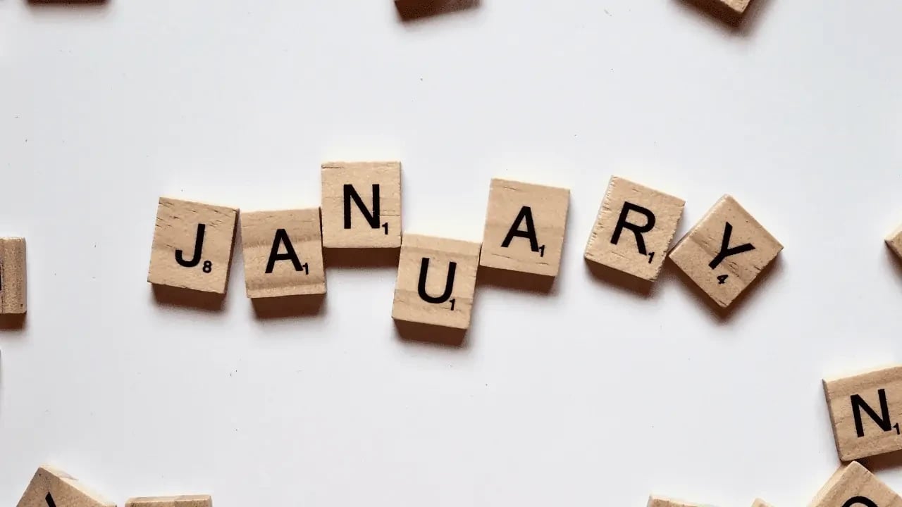 Wooden letter tiles spelling "JANUARY" on a white surface, indicating the start of the new year.