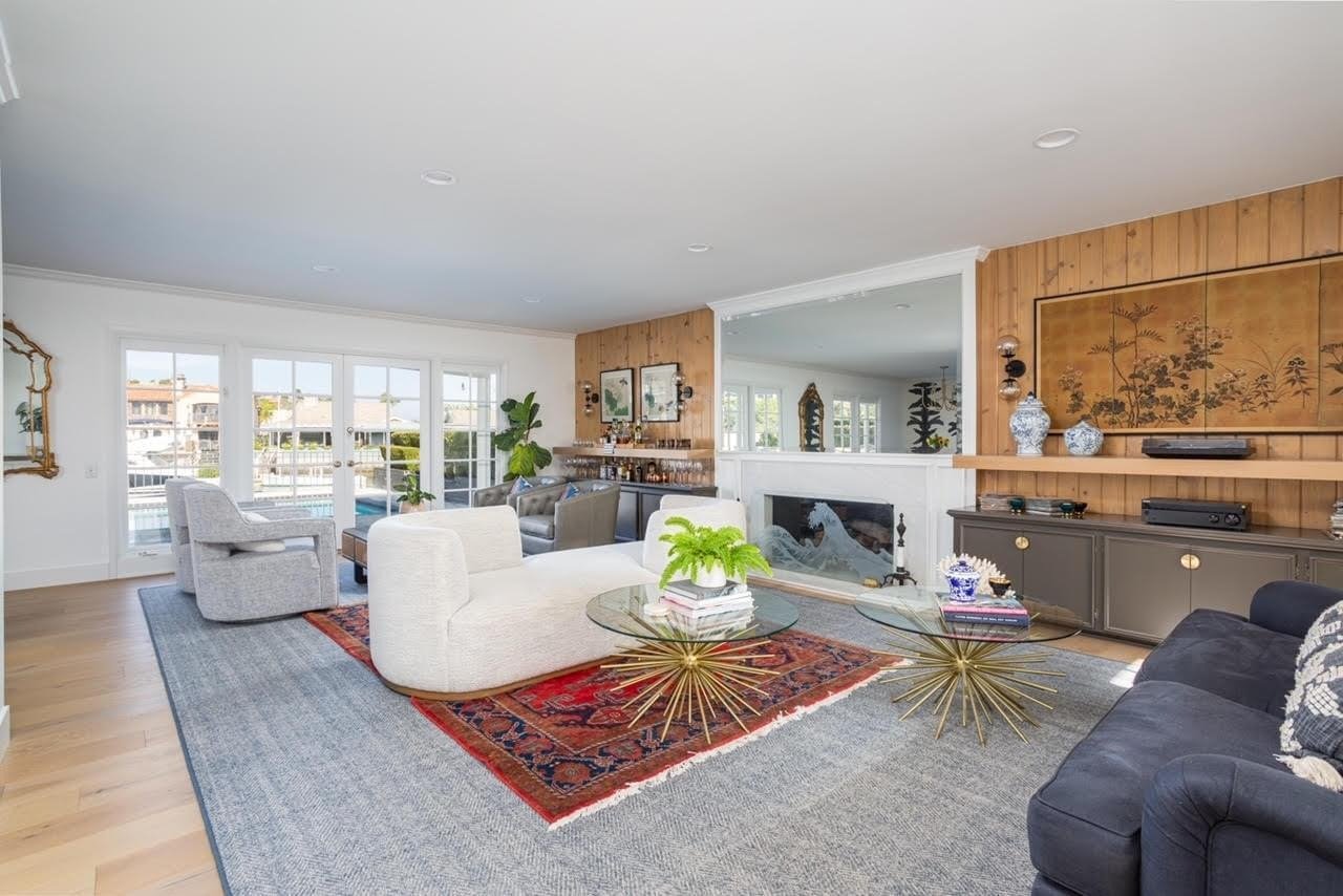  A cozy living room with a navy sofa, a fireplace, and a light wood paneled wall. French doors lead to a deck.