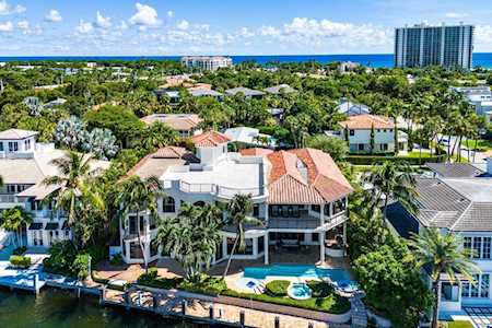 Waterfront home with a terracotta tile roof and backyard pool beside a canal, with the ocean beyond.