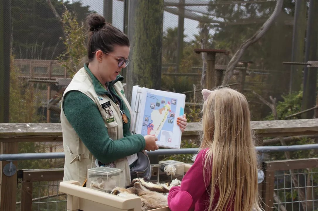 Children participating in a hands-on educational program with a zookeeper, examining biofacts and learning about animal adaptations.