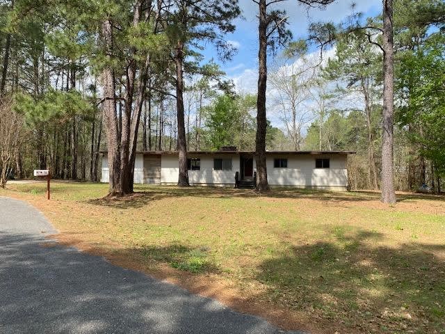 A single-story house in 88 Prospect Pl with a large, open yard surrounded by tall trees. The house is set back from the road, providing a private and secluded feel.