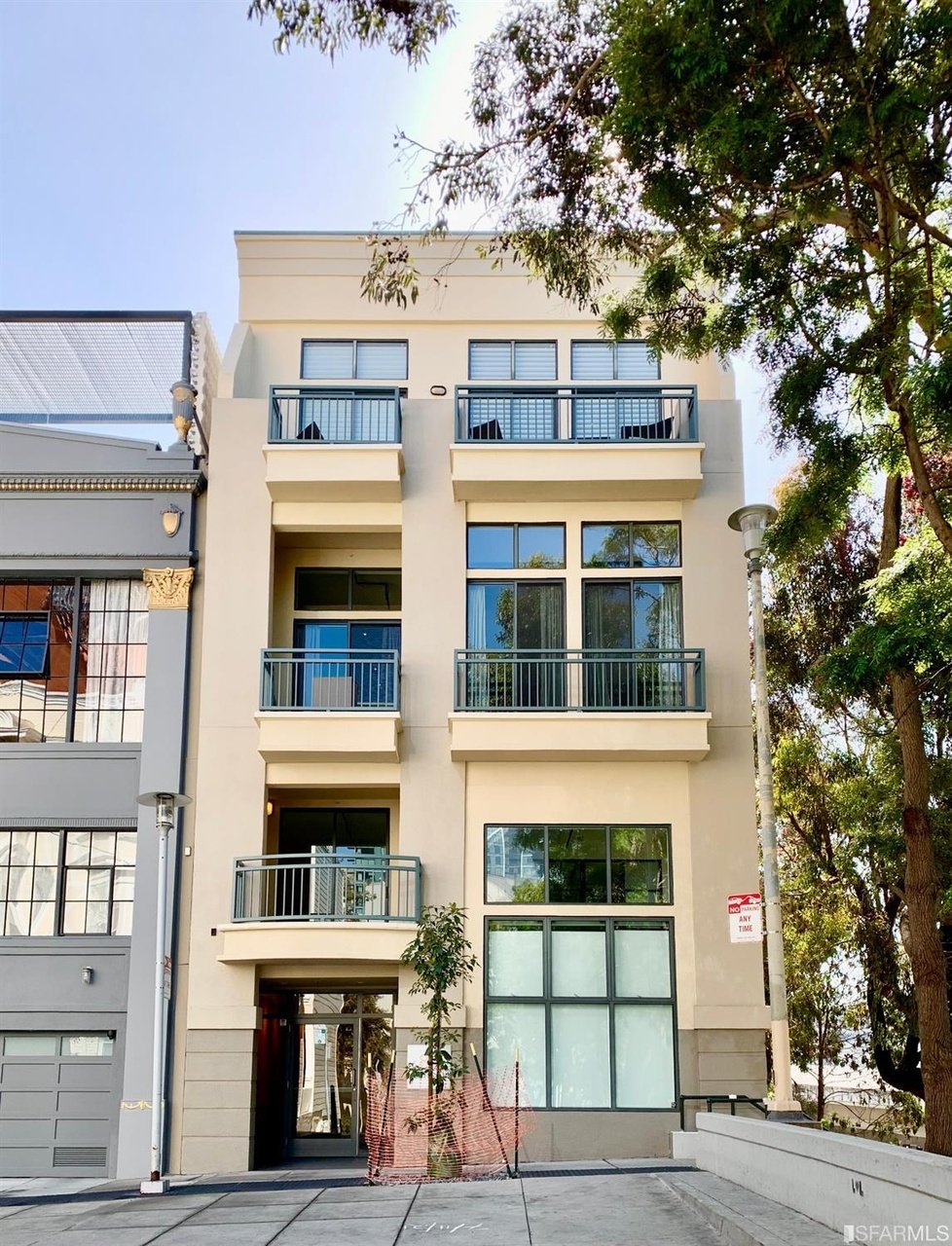 Cream-colored multi-story building with dark-framed windows, metal-railed balconies, and a recessed entrance.