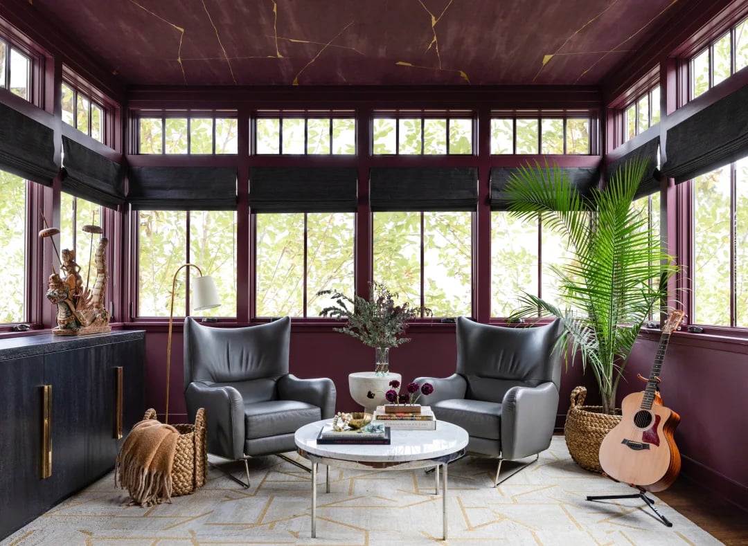 Sitting room with a plum-and-gold ceiling, burgundy trim, tall windows, and two gray armchairs.