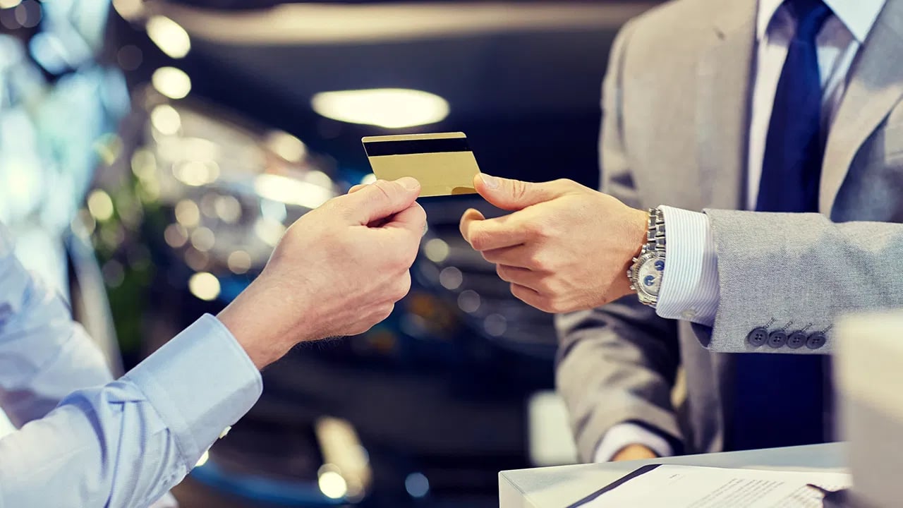 Two people exchange a credit card across a counter.