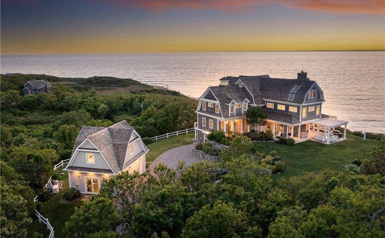 Coastal home and separate cottage beside the ocean, with sunset light reflecting on the water.