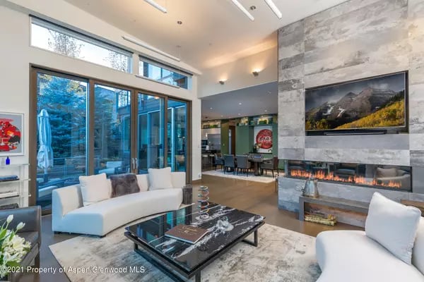 Contemporary living room with floor-to-ceiling glass doors and a tall stone fireplace.