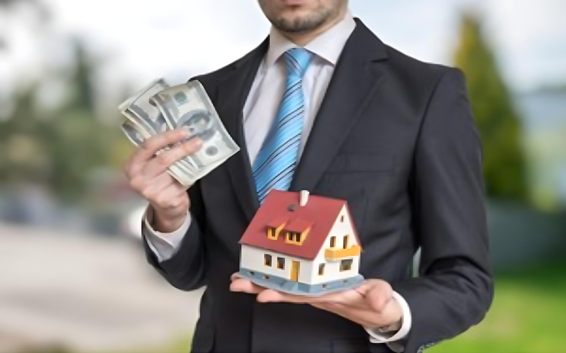 Businessman holding cash and a model house