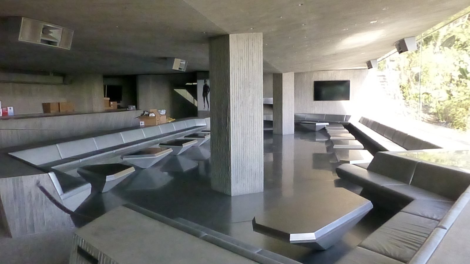 Inside Club James at the Sheats-Goldstein estate: board-formed concrete columns, low built-in seating, and angular tables in a dark, sculptural nightclub space.