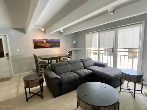 Living room with a dark sectional, dining area, and sliding doors to a balcony.