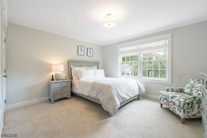 Staged bedroom with a gray bed, white bedding, large sunny window, and floral armchair.