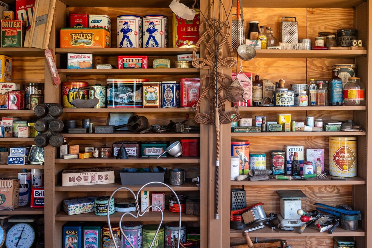 a collection of vintage tins, kitchenware, and memorabilia on wooden shelves