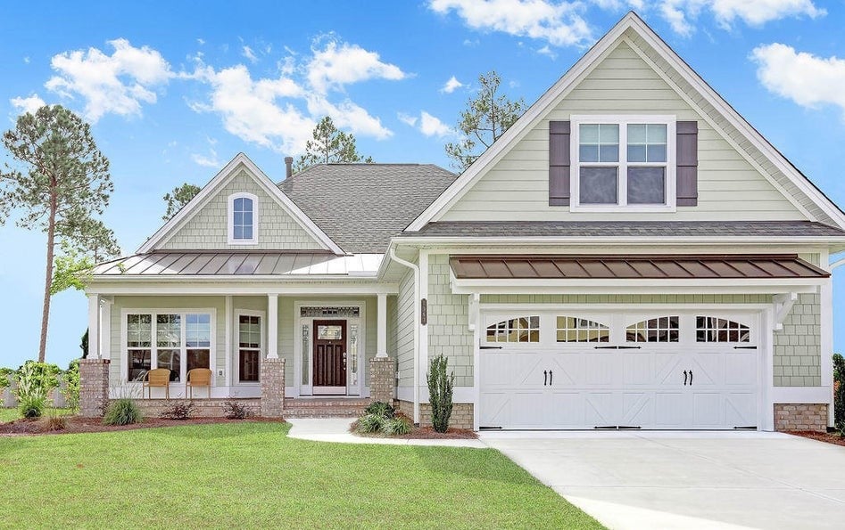 Pale green two-story house with a covered porch, double garage, and broad front lawn.