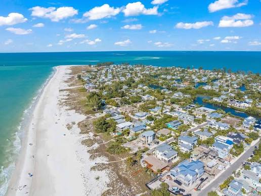 Aerial view of Anna Maria Island homes along a white-sand beach and turquoise Gulf waters.