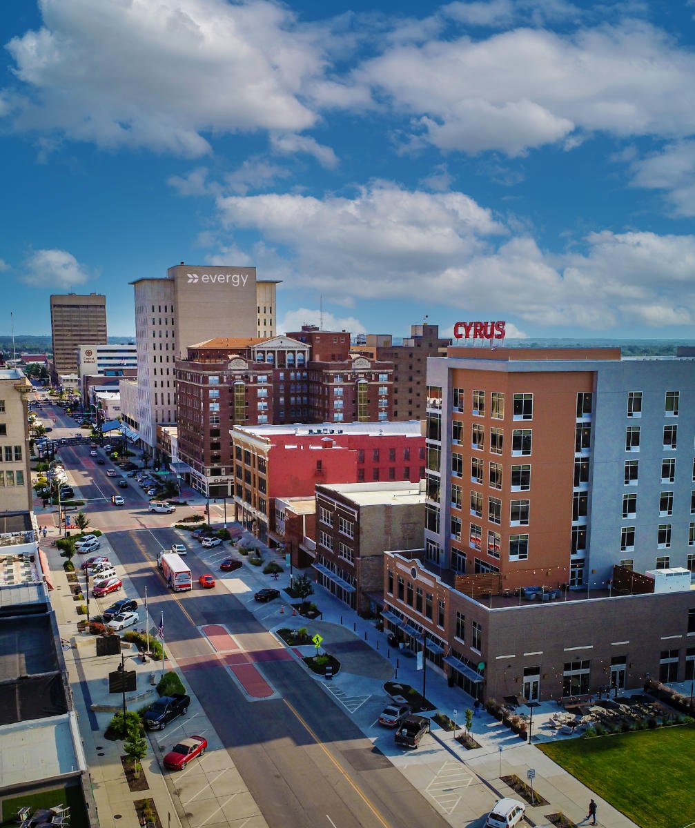 Downtown Topeka skyline with the Evergy building and CYRUS sign above a busy street.