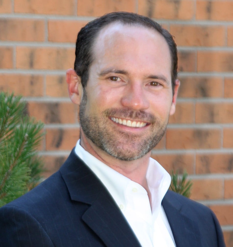 Ryan Buckley smiling in a navy suit and white shirt.