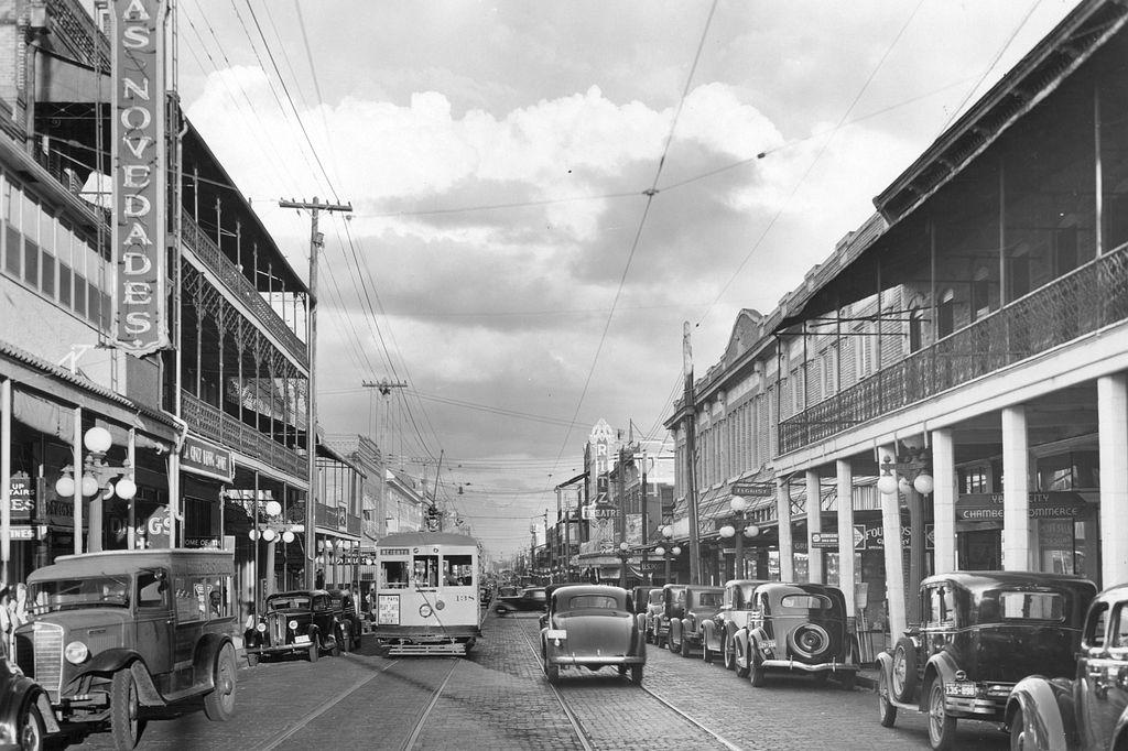 Historic 1925 photograph of Seventh Avenue in Ybor City, Tampa, Florida, showing vintage storefronts and a glimpse of Old Tampa before modern development.