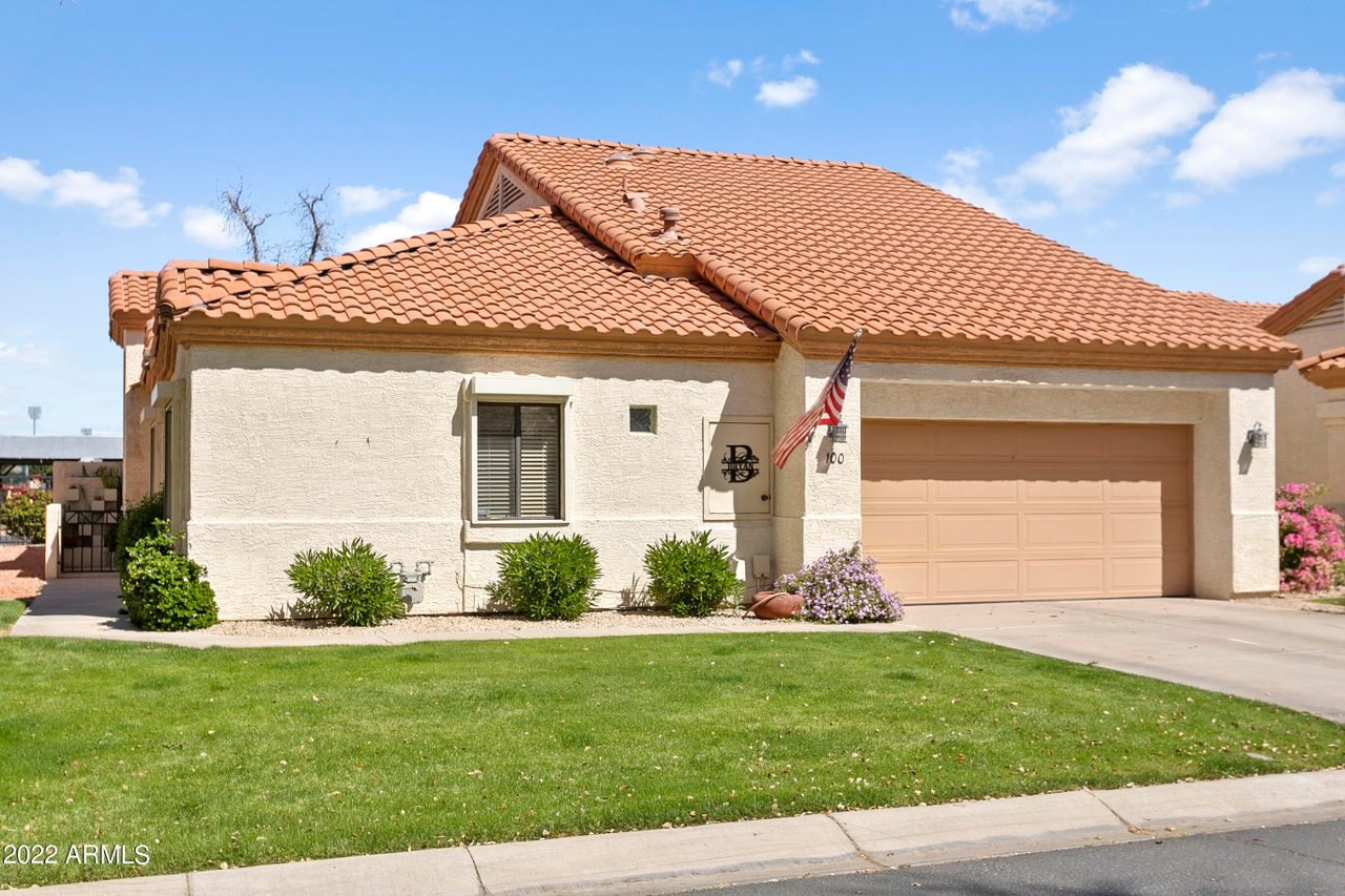 Stucco home with a terracotta tile roof, two-car garage, and American flag.