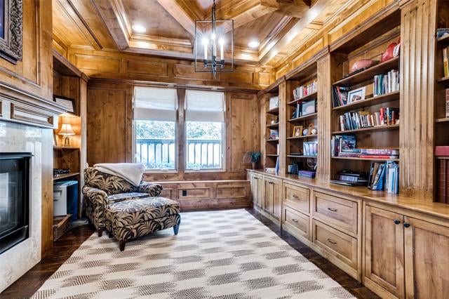 Wood-paneled library with built-in bookshelves, a fireplace, and a patterned armchair.