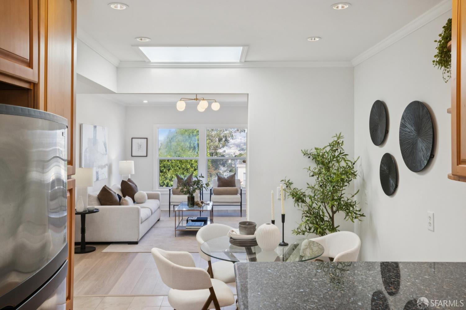 Open-plan kitchen and living room with wood cabinetry, granite island, and large windows.