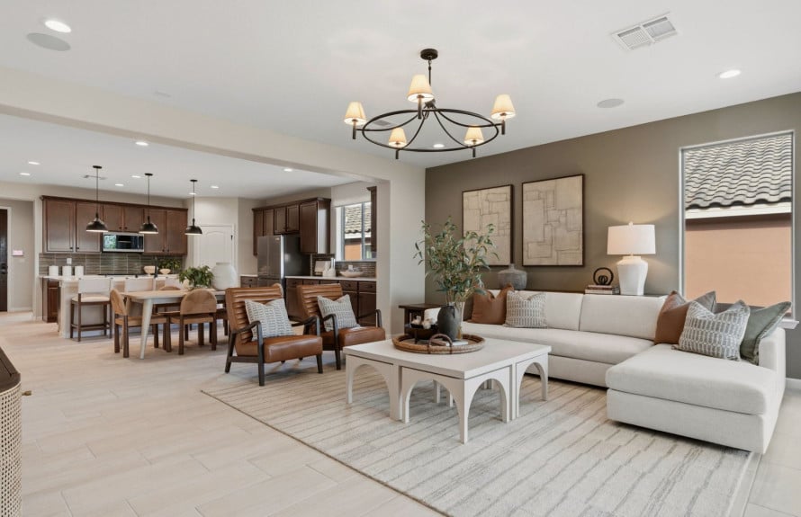 Open-plan living room and kitchen with a white sectional sofa, dark wood cabinets, and dining area.