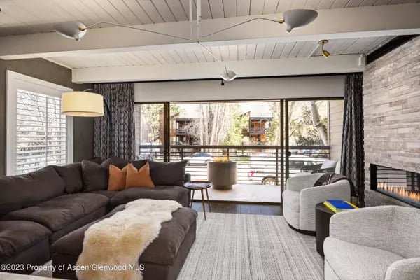 Living room with a dark sectional, stone fireplace, and glass doors opening to a balcony.