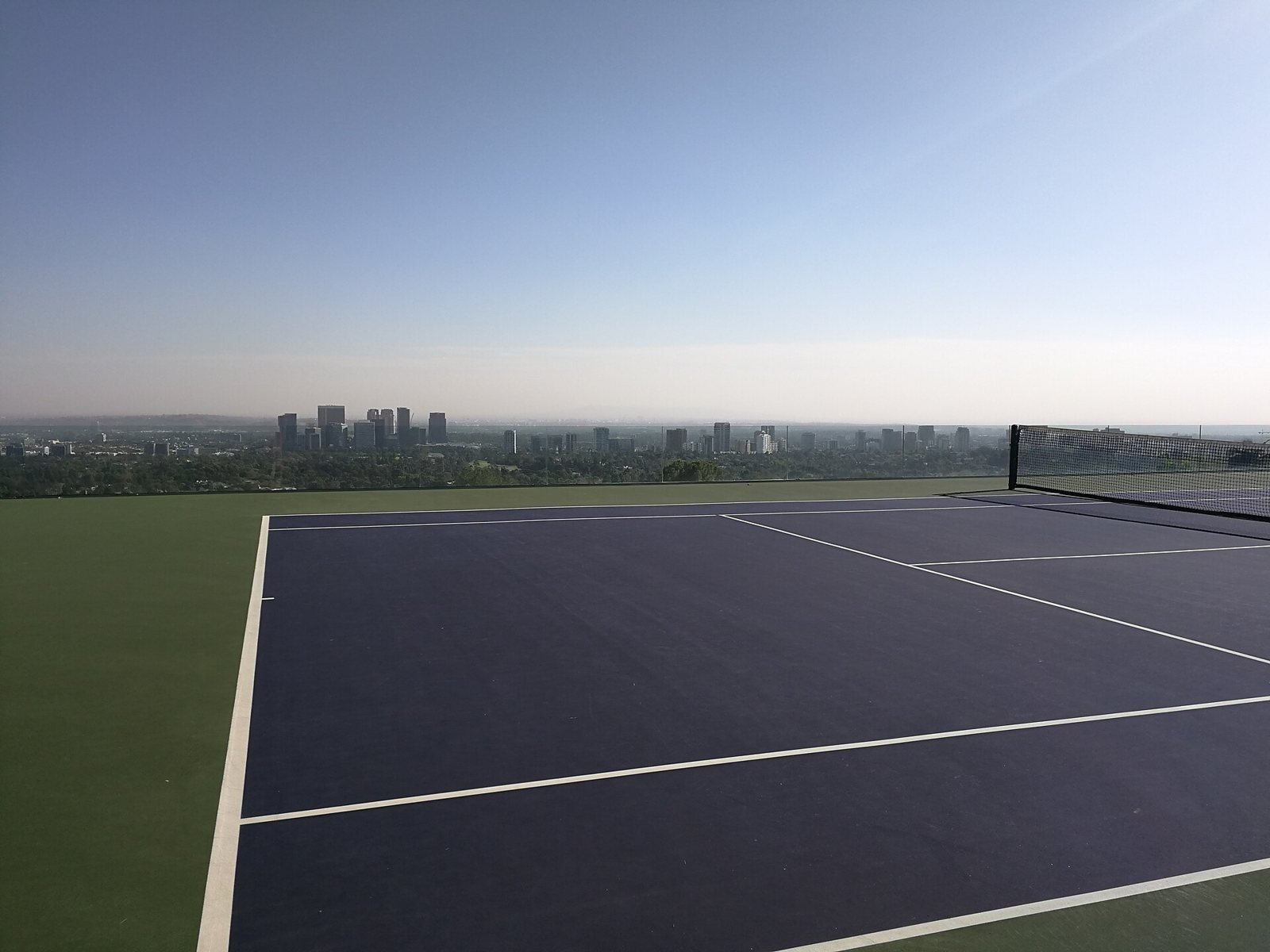 The infinity-edge tennis court on the Sheats-Goldstein estate with the Century City skyline and Los Angeles basin beyond.