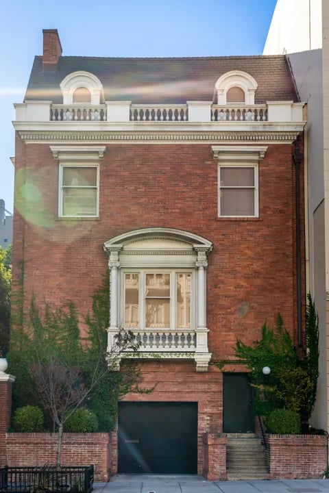Red brick townhouse with white classical trim ornate bay window and balustrade in San Francisco