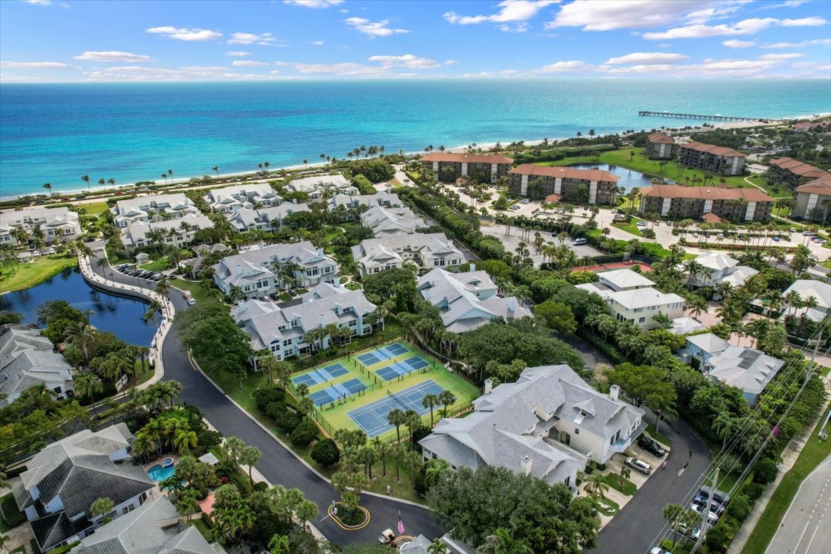 Aerial view of Sea Colony condominiums, tennis courts, and beachfront along a turquoise ocean.