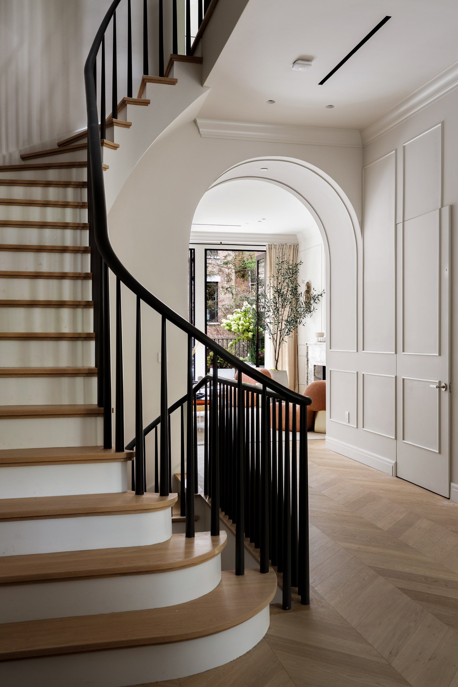 34 West 12th Street — curved staircase framing a view through the arched passage
