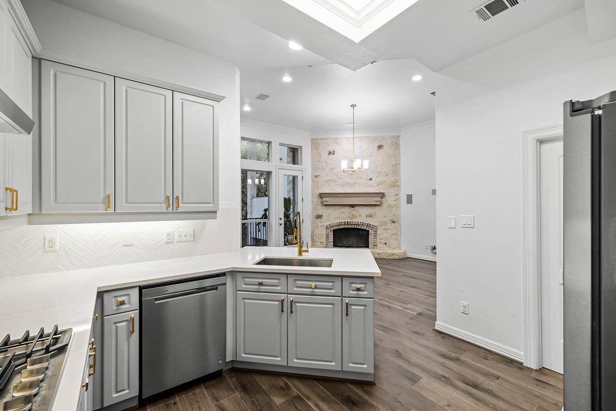 Kitchen open to the family room and stacked-stone fireplace, Barton Hollow, Westlake, Austin.
