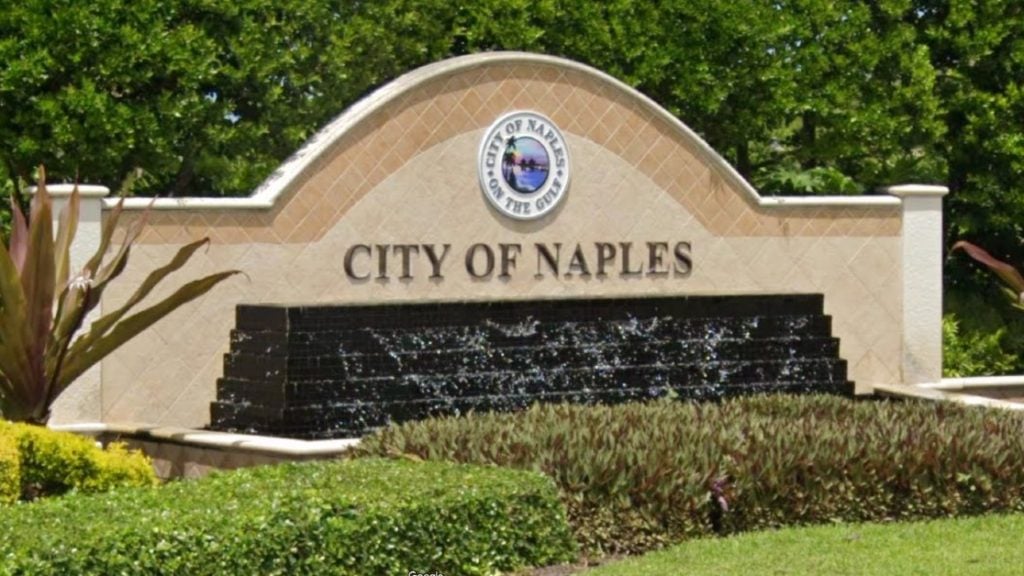 City of Naples entrance sign with a circular seal and water feature.