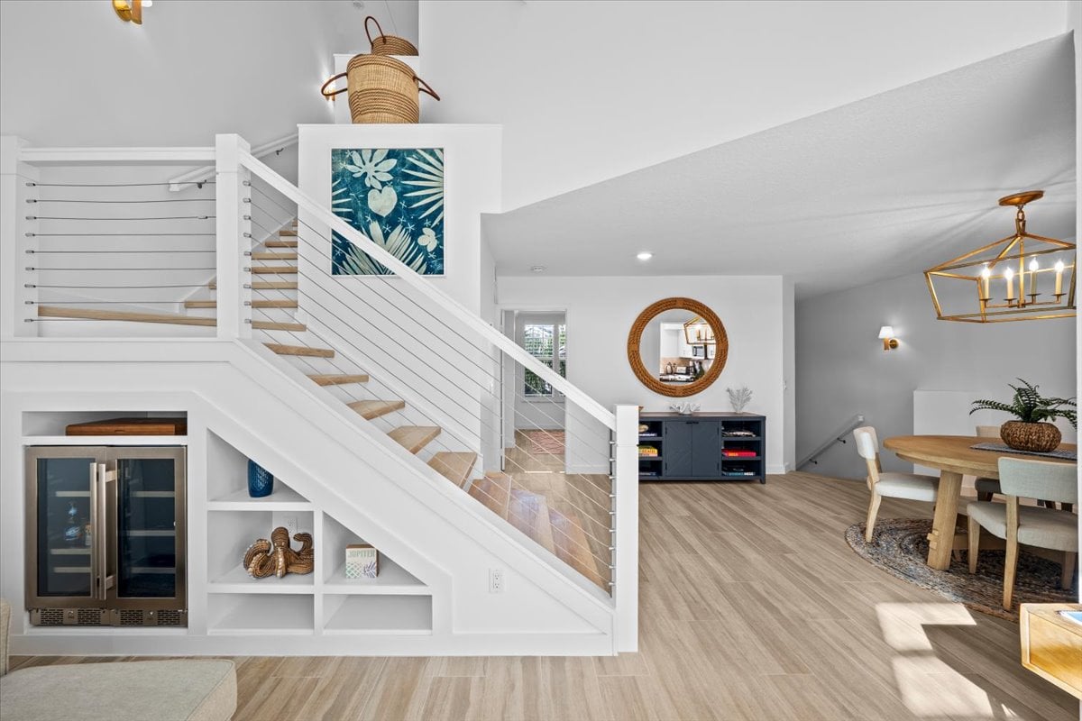 Condominium interior with a cable-railing staircase, built-in wine refrigerator, and dining area.