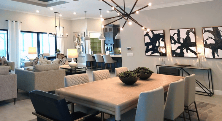 Open-plan dining area with a wood table, upholstered chairs, and a branching chandelier.