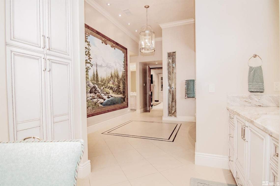 Upscale bathroom with white cabinetry, a marble counter, and a large landscape mural.