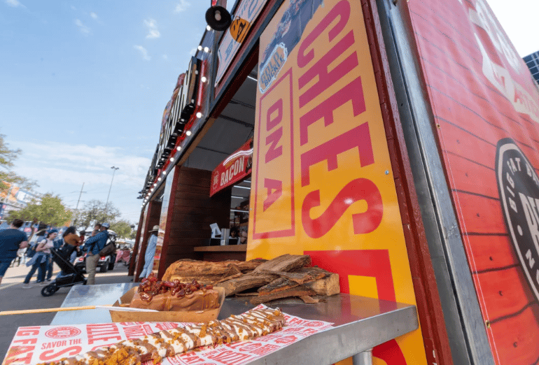 Deep-fried treats and bacon-wrapped foods displayed at an outdoor rodeo concession stand.