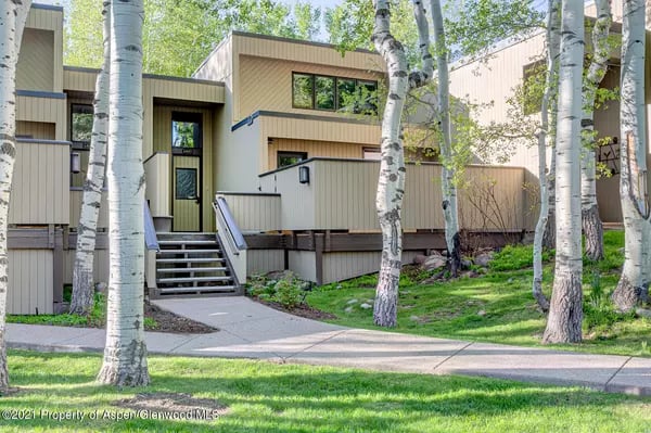Modern tan-and-gray home with an entry staircase among aspen trees.