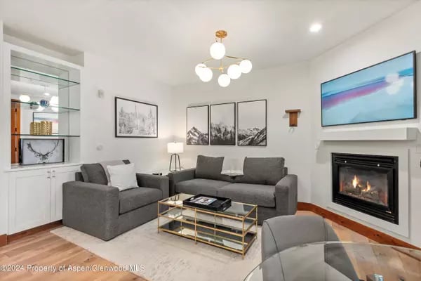 Living room with gray seating, glass coffee table, fireplace, and wall-mounted TV.