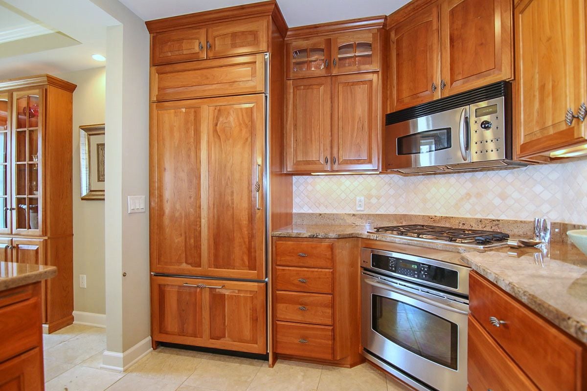 Kitchen with warm wood cabinetry, stone countertops, and stainless steel appliances.