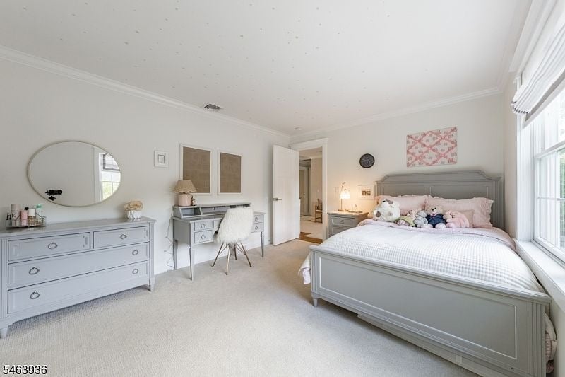 Bedroom with a gray bed, plush toys, matching dresser and vanity, and tall windows.