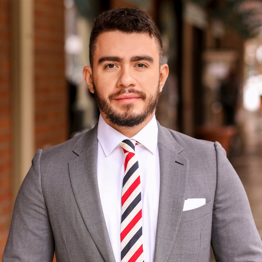 Luis Ramirez wearing a gray suit and striped tie.