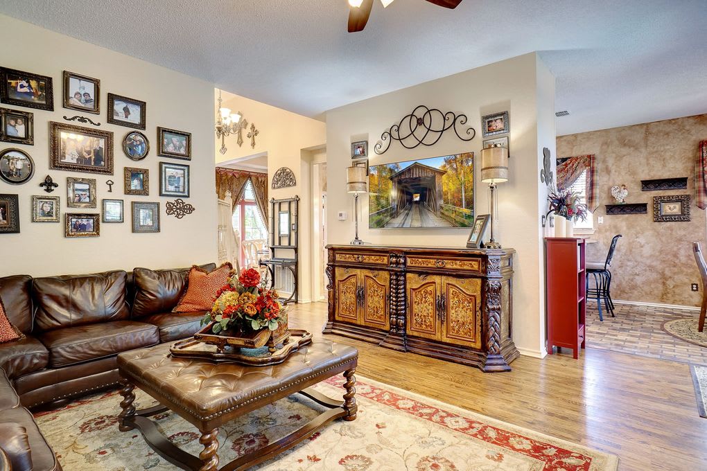 Furnished living room with leather sofa, ornate sideboard, and an adjoining dining area.