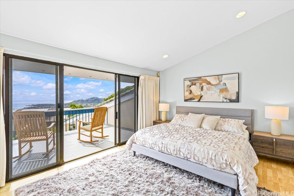 Bedroom with a king bed and sliding doors opening to a balcony with ocean and mountain views.