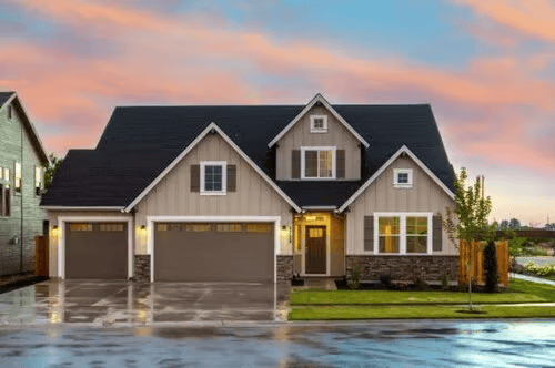 Two-story home with a dark gabled roof and double garage at dusk.