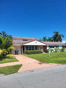 Single-story home with a red-tile roof, palm trees, and a curved front walkway.
