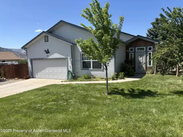 Gray single-story home with a two-car garage, covered entry, and front lawn.