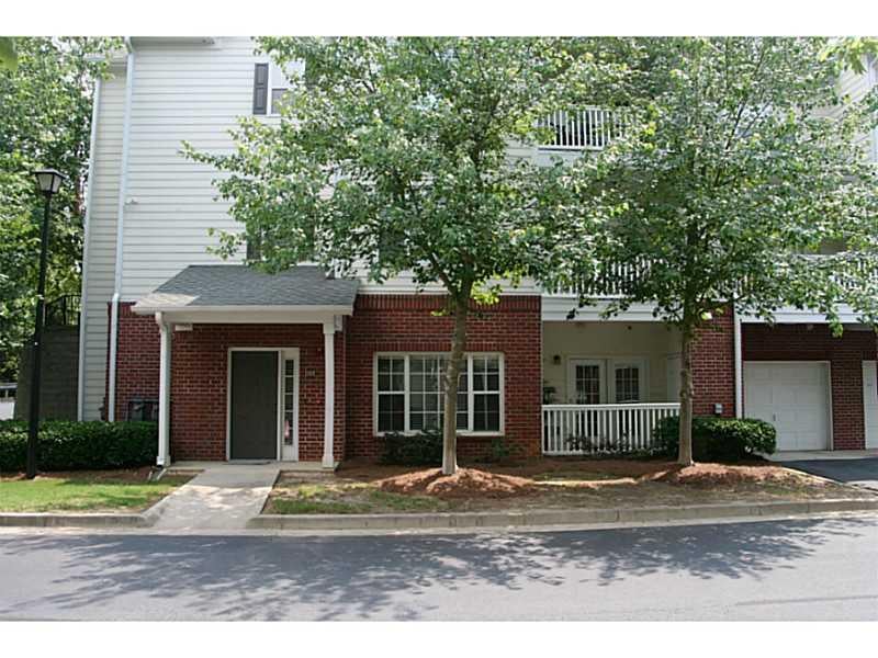 Multi-story brick and white-sided home with a covered entry, balcony, and attached garage.