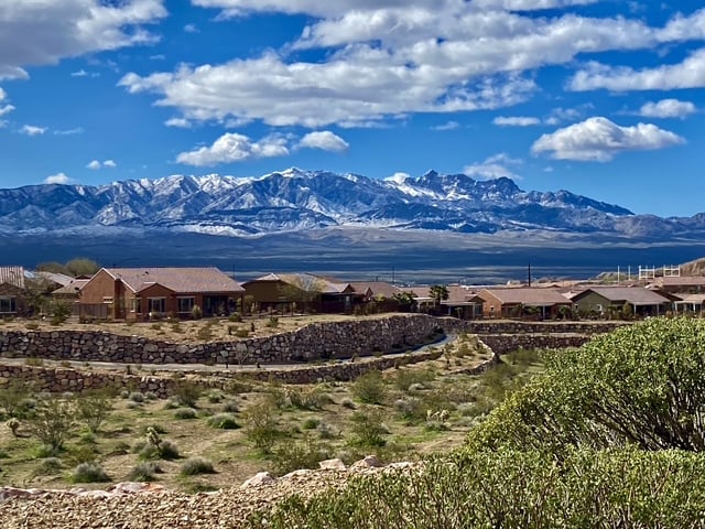 Mesquite neighborhood homes and stone walls with a mountain range in the background.