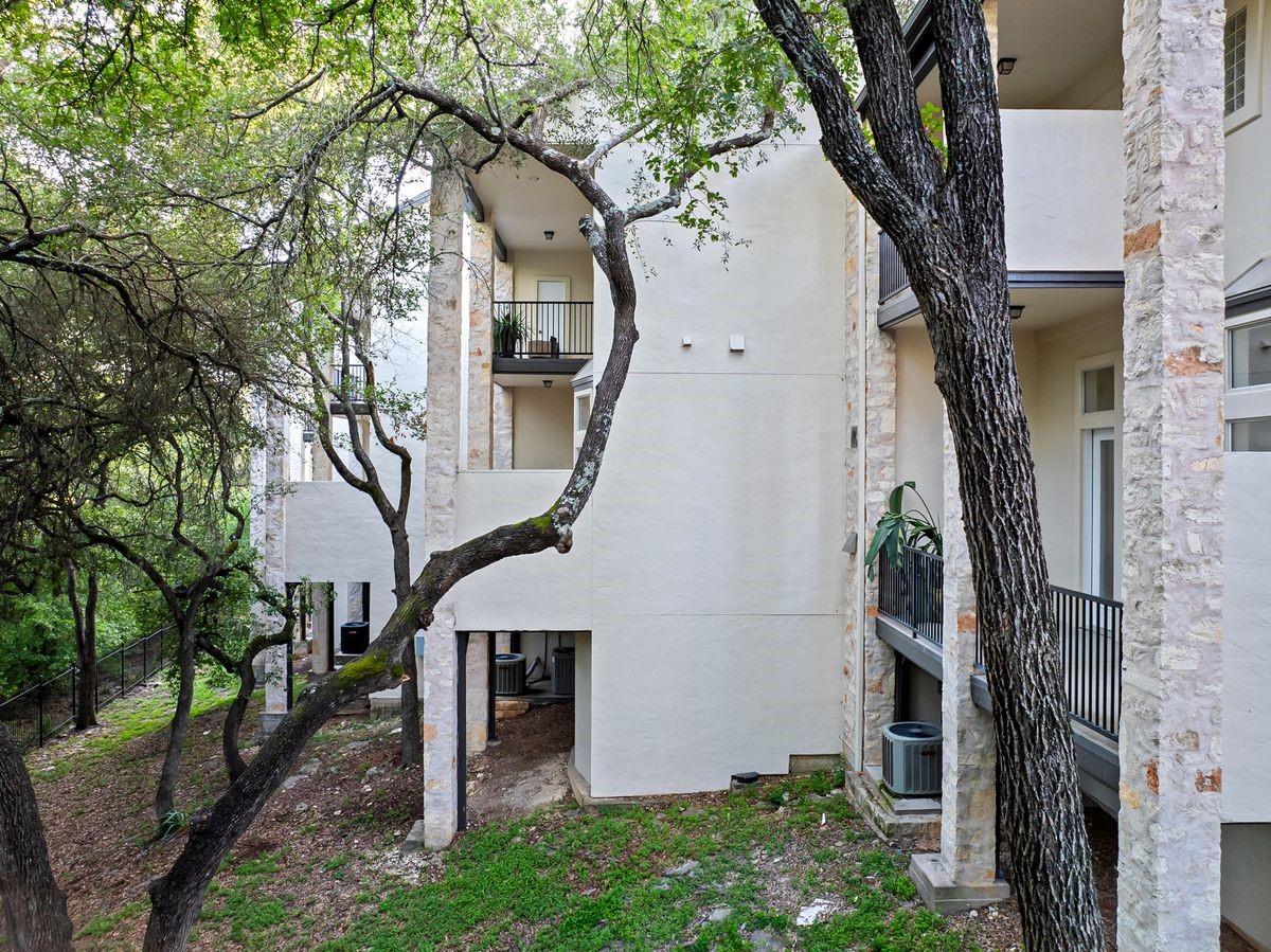 Exterior elevation in stone and stucco under mature oak trees, Barton Hollow, Westlake, Austin.