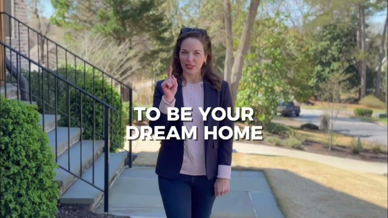 Woman in a navy blazer gestures on a home’s front walkway beneath the words “TO BE YOUR DREAM HOME.”