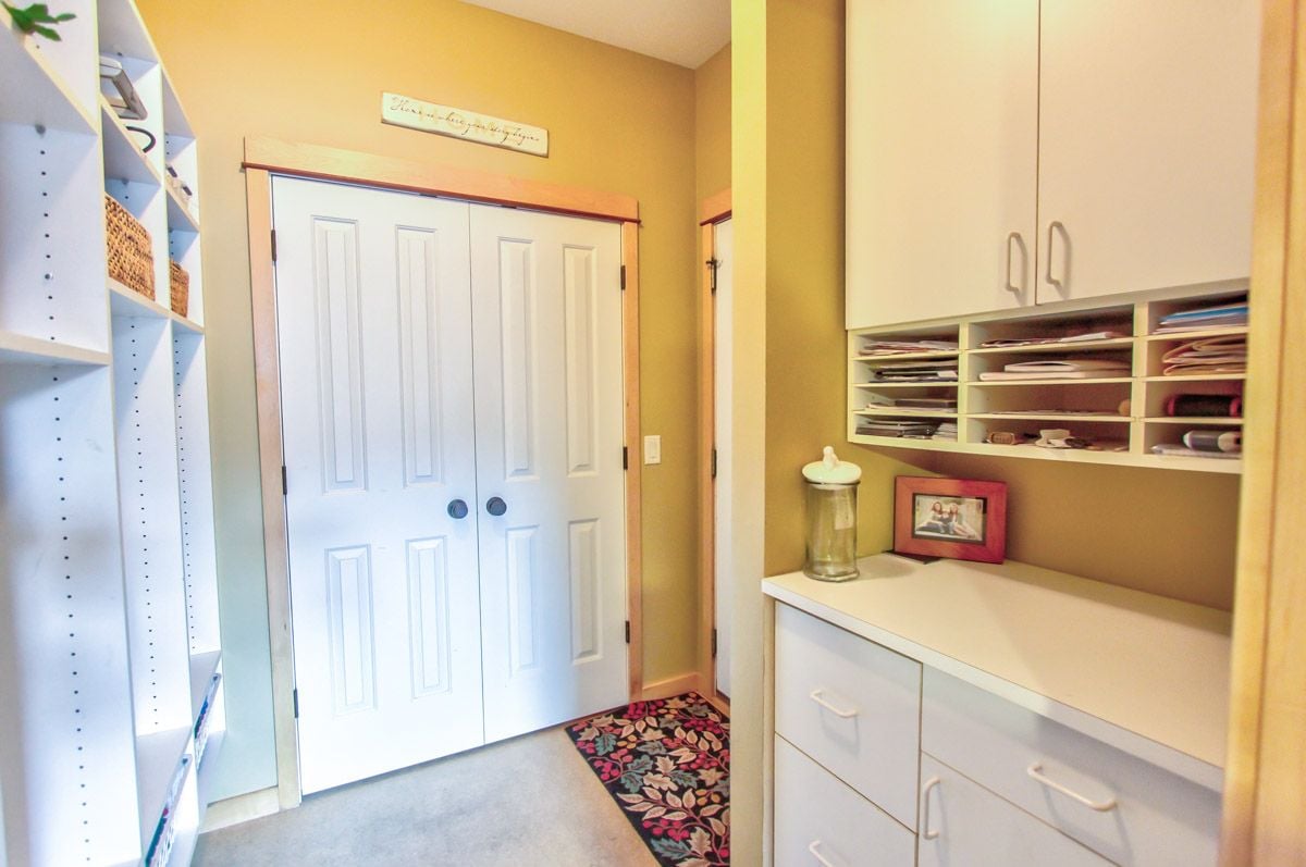 Home storage room with built-in cabinets and shelves beside double closet doors.